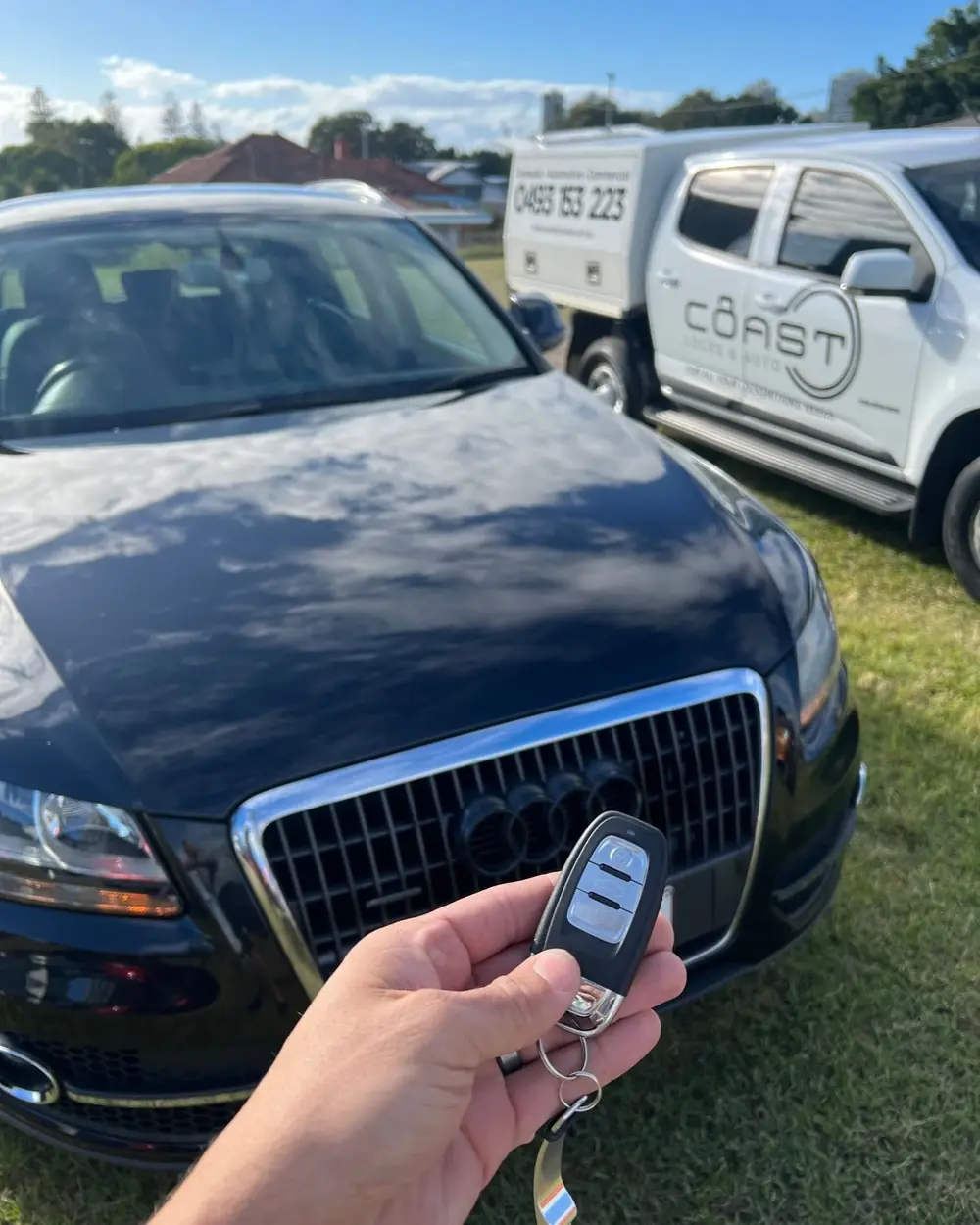Car key held in front of a vehicle and locksmith van